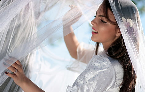 woman wearing white dress holding veil