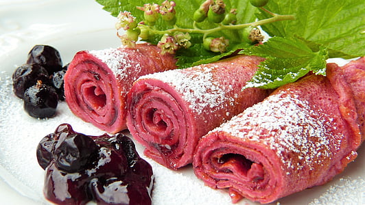 selective focus photo of swiss roll top with powered sugar and black berries