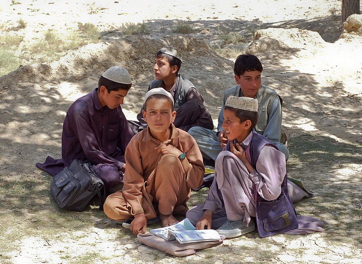 five boys sitting on gray surface during daytime