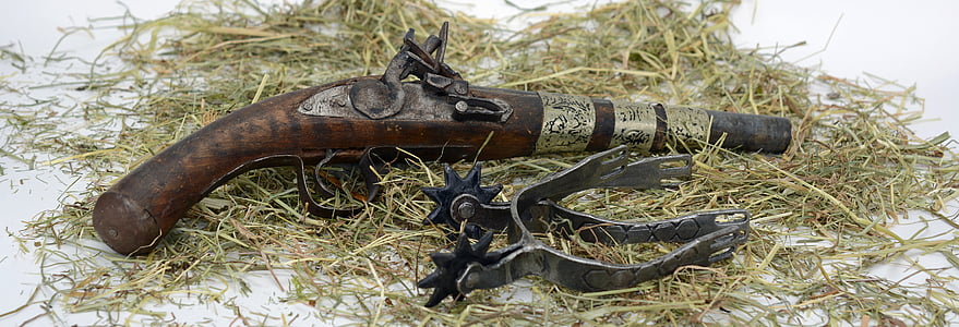 brown and black flintlock pistol and black metal spur