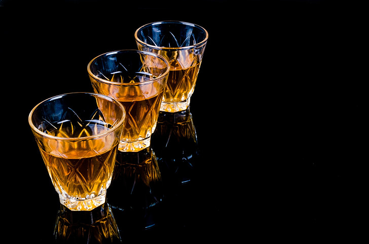 three clear shot glasses on black surface