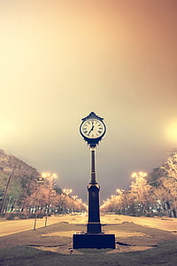 photo of pedestal clock on road at nighttime
