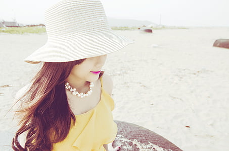 photography of sitting woman wearing summer hat during daytime