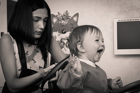 grayscale photography of girl doing hair cut on child
