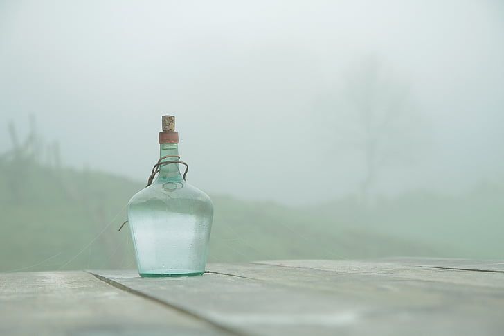 clear glass bottle on gray wooden table