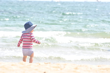 baby walking gray, red, and pink striped long-sleeved shirt near body of water