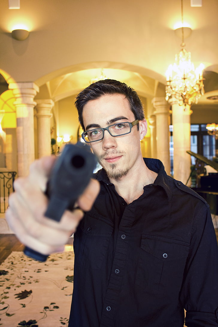 man wearing black dress shirt pointing gun forward