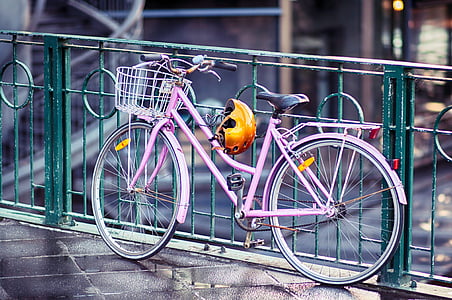 pink rigid bicycle beside green metal railings