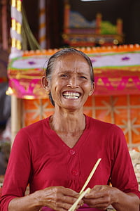 woman smiling while holding yellow string on front of orange and yellow altar
