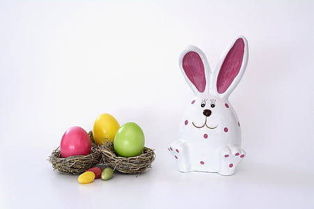 white and pink rabbit ceramic figurine beside Easter eggs