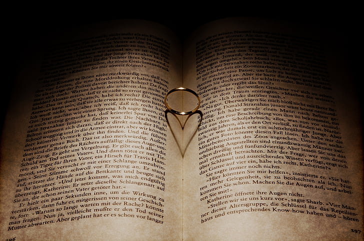 silver-colored ring between book forming heart shadow