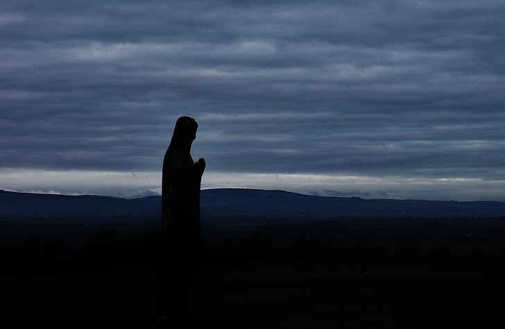 silhouette of statue near hill at dawn