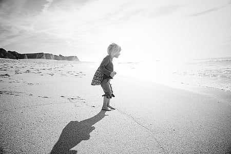 child walking on seashore during daytime