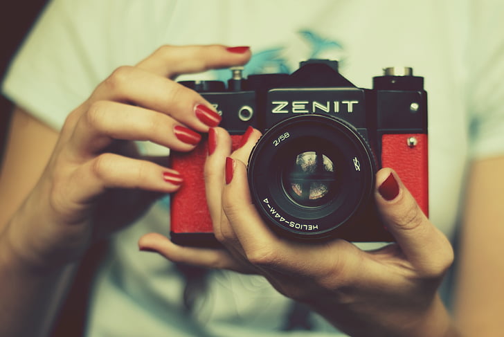 person holding red and black Zenit SLR camera