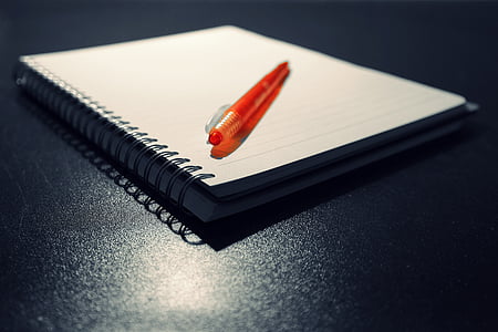 orange click pen on notebook