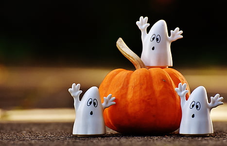 three plastic ghost near pumpkin