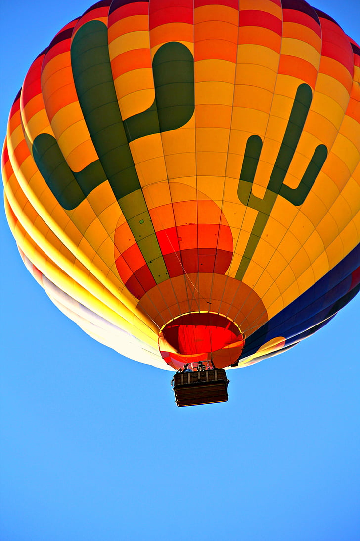 photo of yellow, red, and blue hot-air balloon in flight