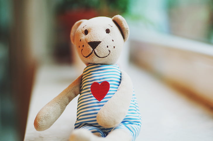 beige bear wearing blue rompers plush toy close-up photography