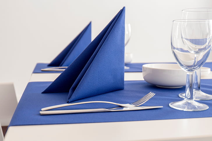 blue table napkin near silver fork and knife on top of blue textile