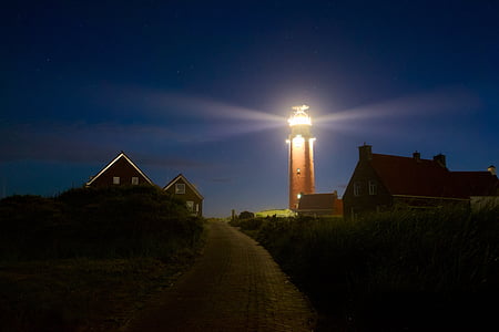brown lighted lighthouse between houses