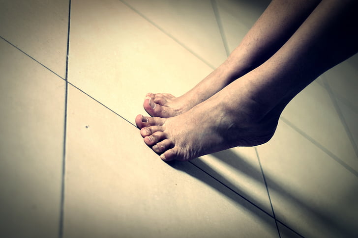person's feet on white ceramic tiles