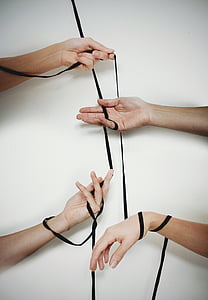 four person's hand holding black cord
