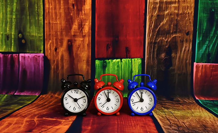 three black, red, and blue dual-bell alarm clocks