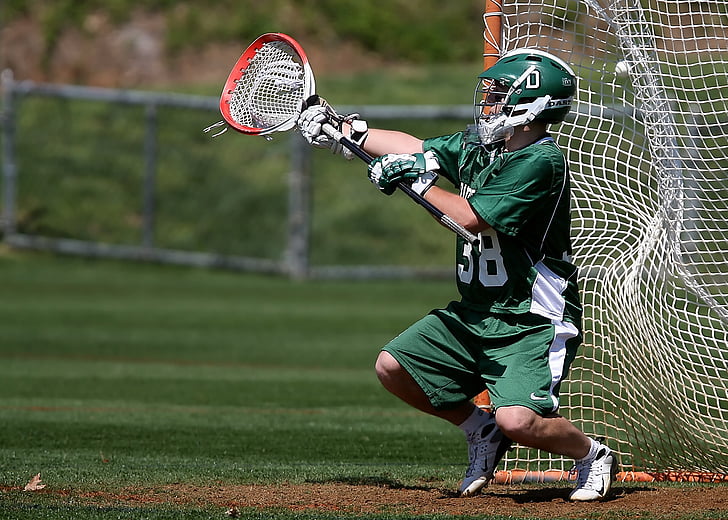 player in green jersey and shorts holding lacrosse stick