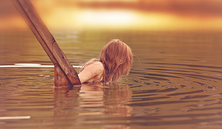 woman dipping on body of water