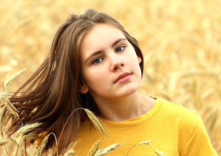 woman in yellow crew-neck shirt surrounded by yellow petaled flowers
