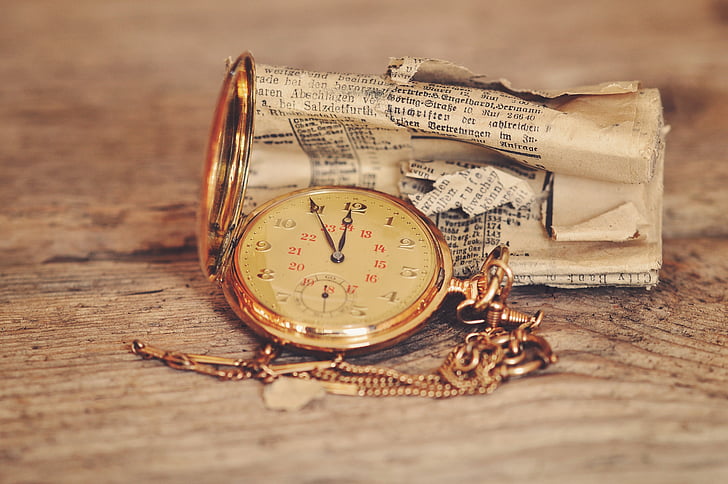 round gold-colored analog pocket watch at 11:55