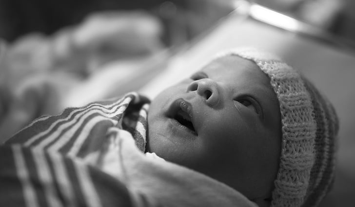 greyscale photo of baby in cap