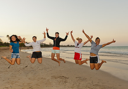 five women jumping on beach