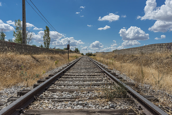 black and gray railway between brown grasses under clear blue sky during daytime