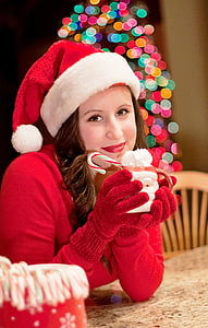 woman in Santa hat holding a pastry in cup