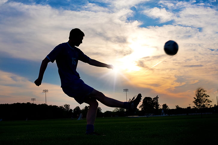 silhouette photography of man kicking ball