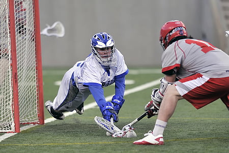 two men playing lacrosse in front of net