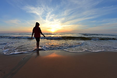 woman walking on sand towards sea