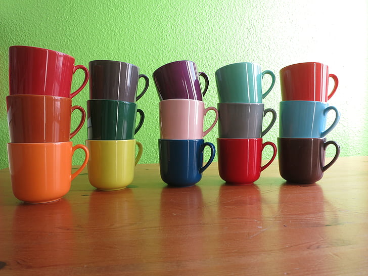assorted-color ceramic mugs on brown wooden table