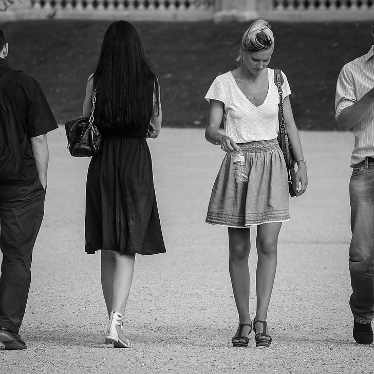 two men and women walking opposite way grayscale photography