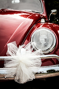 closeup photo of white bow on red Volkswagen Beetle headlight