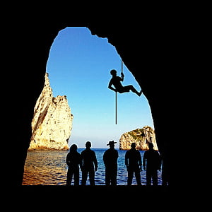 silhouette of person climbing in cave