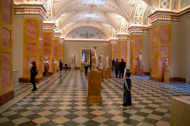 people standing and walking inside museum with statuettes