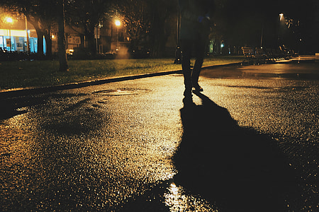 man standing on concrete road during nighttime