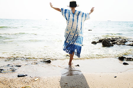 person in white and blue dress standing on sea shore