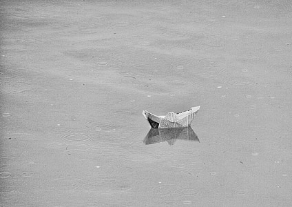 photo of paper boat floating on calm water