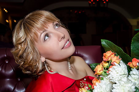 woman wearing red one-shoulder tops holding white and orange petaled flower bouquet