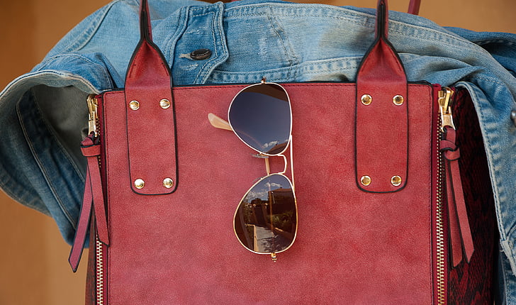 black sunglasses hanging on red leather bag