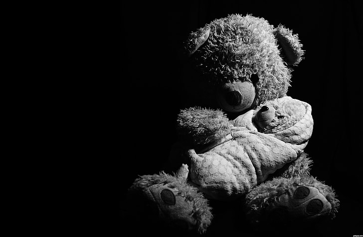 grayscale photography of brown bear plush toy carrying baby plush toy