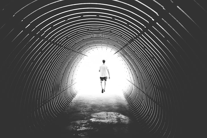 man wearing white shirt and black shorts walking in tunnel
